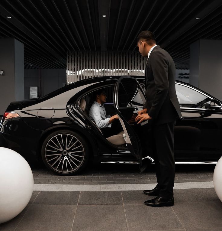 Professional chauffeur in uniform opening luxury car door — corporate car service Cairo